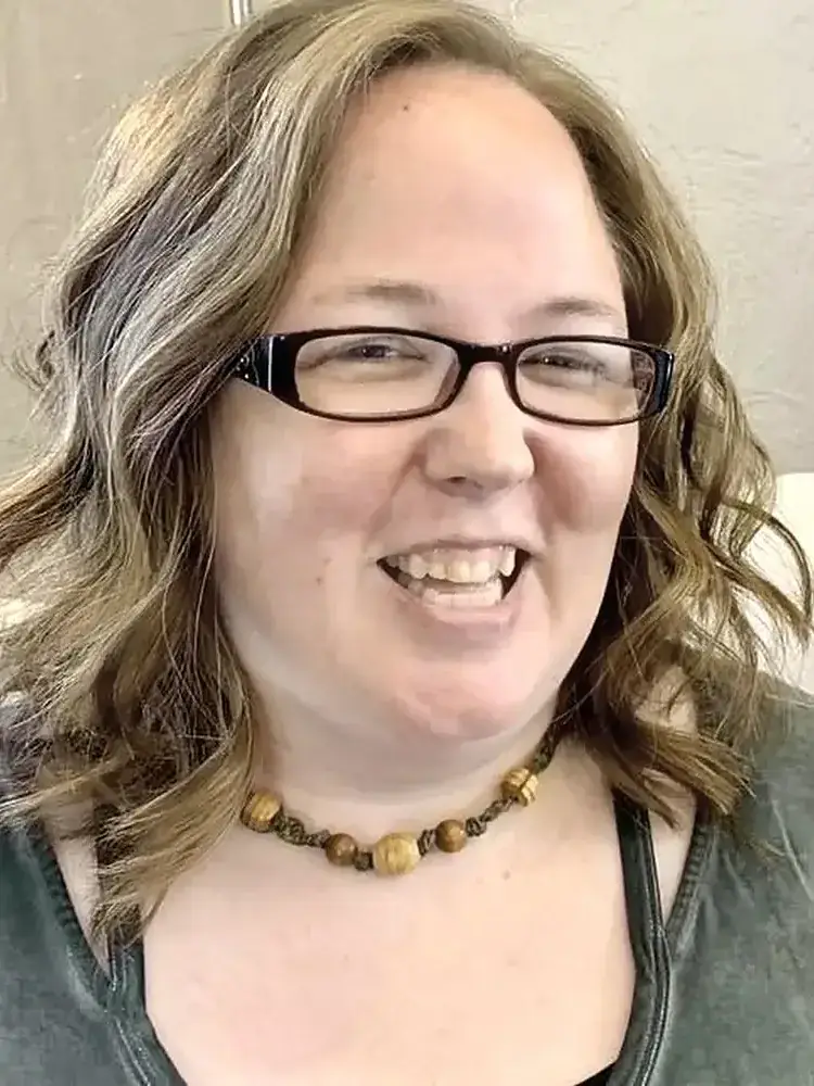 Dr. Crystal Buesing, DC — chiropractor in Le Claire Iowa, smiling warmly in her clinic. Doctor of Chiropractic since 2008, Palmer College of Chiropractic graduate.