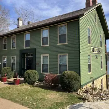 Dr. Crystal's Chiropractic Care at the historic Old Mill House, 419 N. Cody Road, Le Claire Iowa. A welcoming sage-green two-story building with a visible clinic sign.