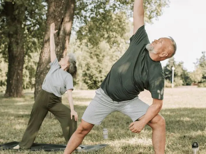 Two people stretching outdoors in a park performing corrective posture exercises, representing the corrective exercise program at Dr. Crystal's Chiropractic Care